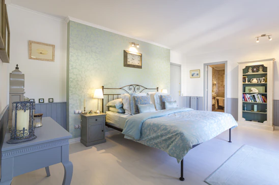 A serene bedroom bathed in soft teal and deep blue hues, with a cozy bed inviting peaceful sleep.