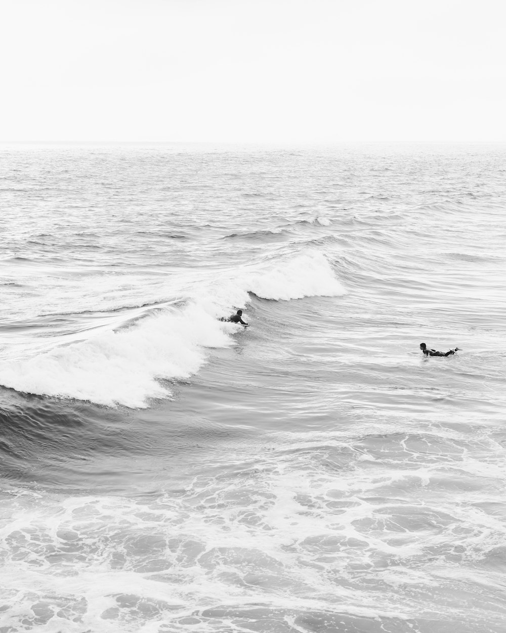 grayscale photo of person surfing on sea waves