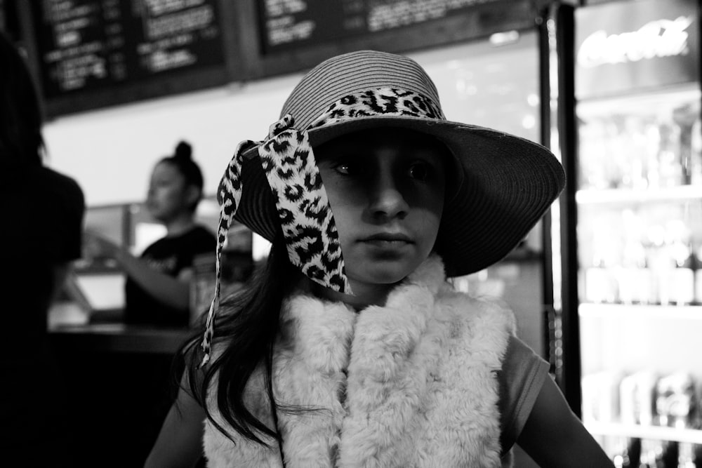 Foto en escala de grises de una mujer con sombrero blanco y negro