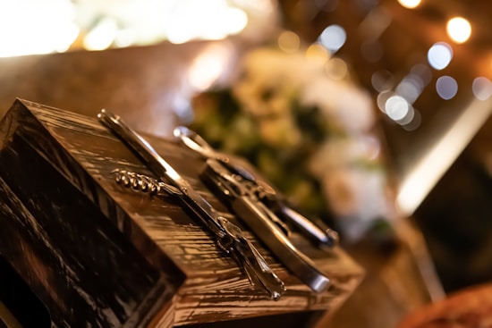 A set of shiny metal corkscrews and bottle openers rests on a wooden surface, with a soft background of warm bokeh lights creating a cozy ambiance.