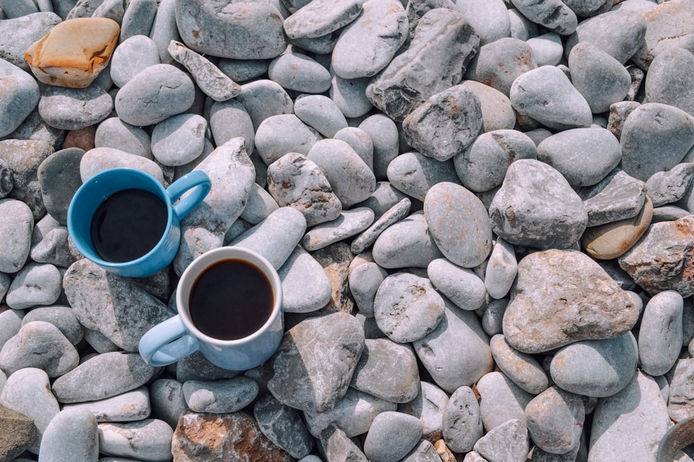 blue ceramic mug on gray and black stones