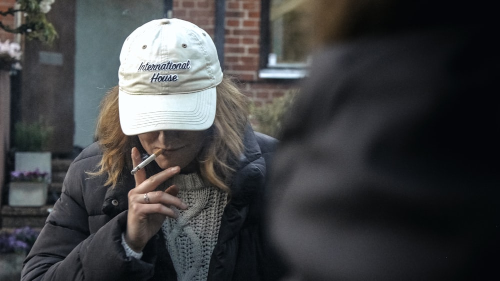 Frau in grauem Strickpullover mit weißer Strickmütze hält Smartphone
