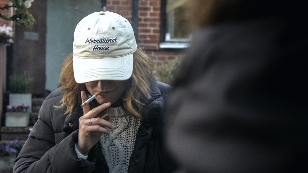 woman in gray knit sweater wearing white knit cap holding smartphone