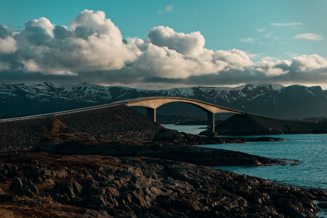 brown bridge over blue sea under white clouds and blue sky during daytime