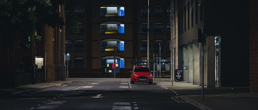 rotes Auto tagsüber auf der Straße in der Nähe des Gebäudes
