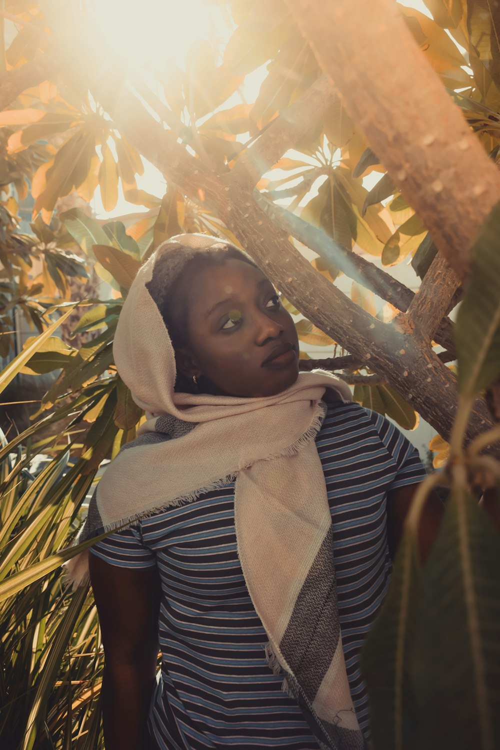 woman in black and white stripe shirt standing near brown tree during daytime