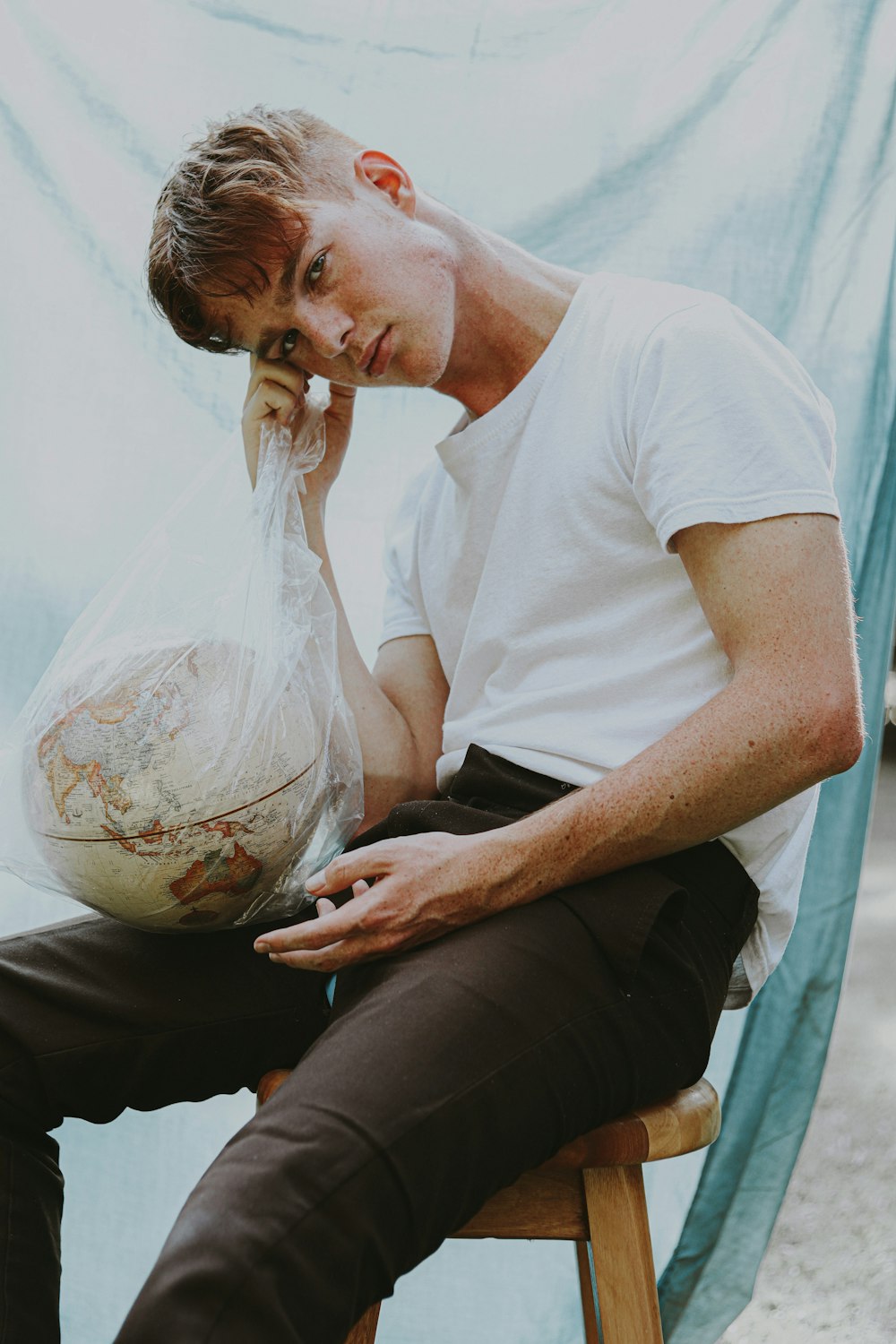 man in white crew neck t-shirt holding clear glass ball