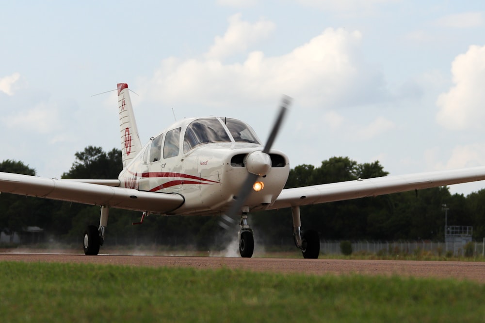 white and red jet plane on green grass field under white clouds during daytime