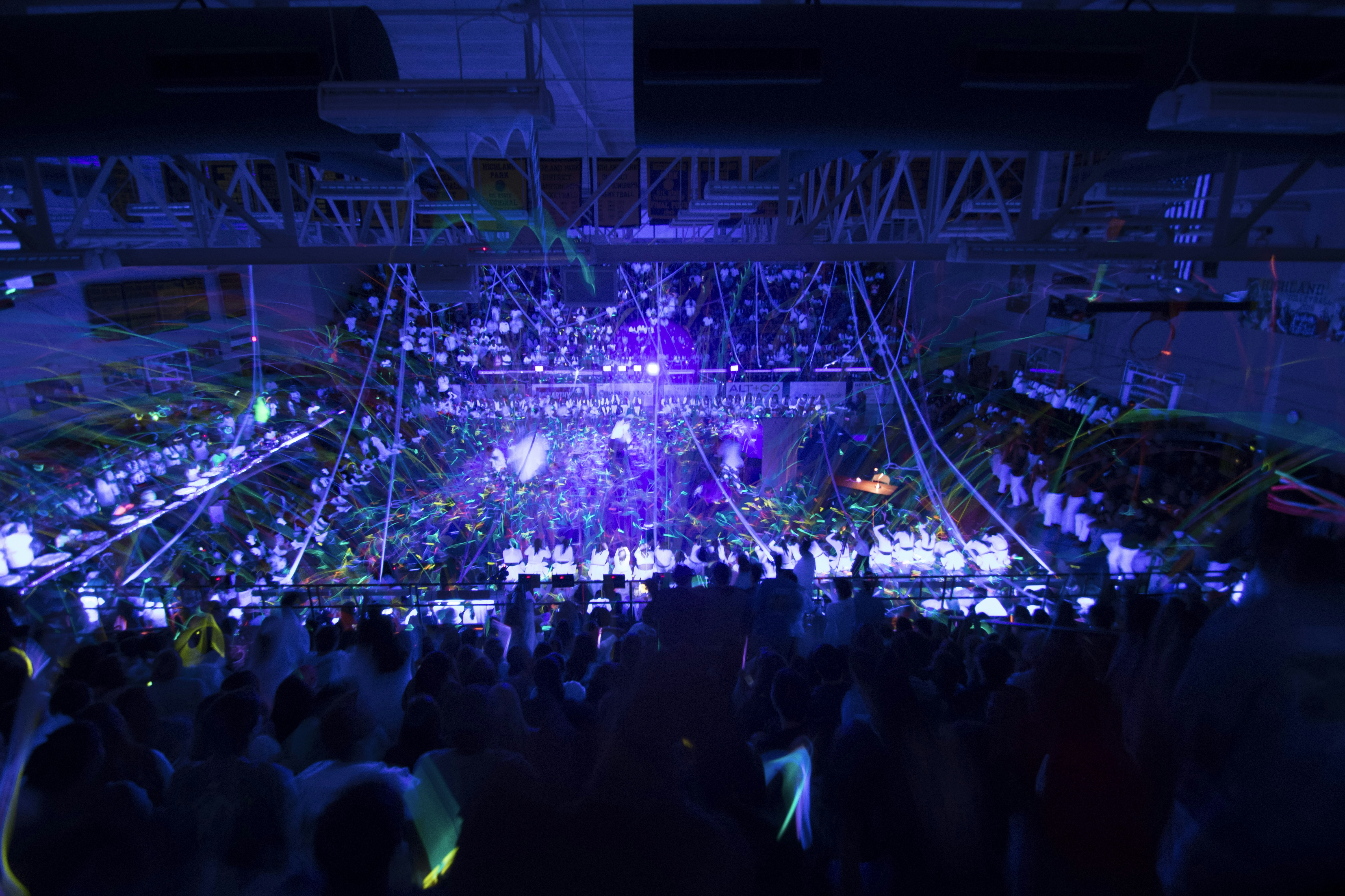 Birthday party with colourful LED lighting, crowd celebrating, confetti in the air, dark venue with vibrant neon colours