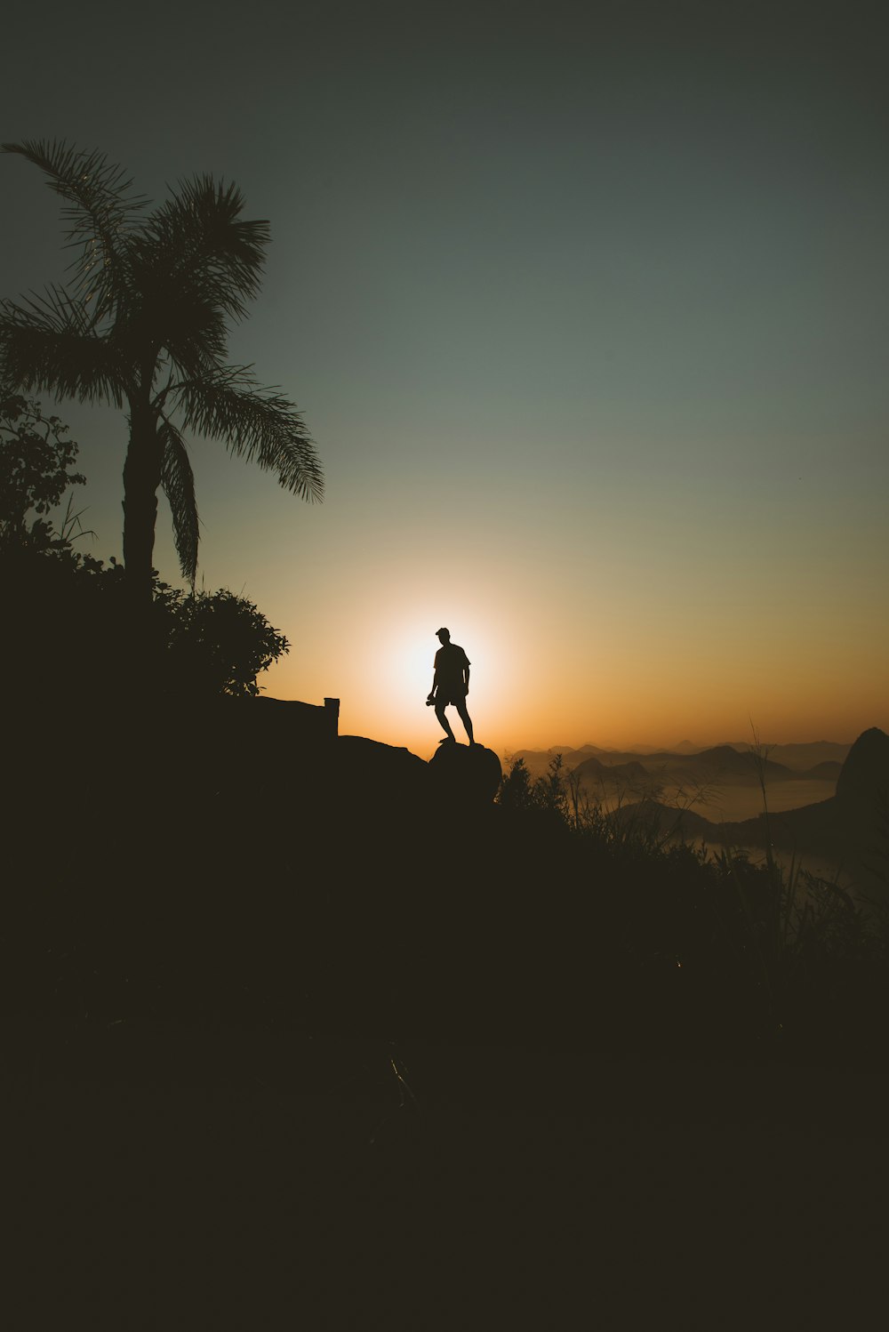 silhouette of man standing on rock formation during sunset