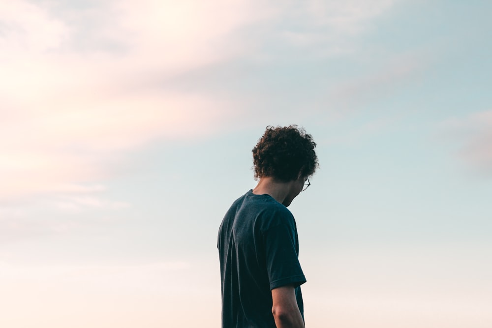 man in black crew neck t-shirt standing under white sky during daytime