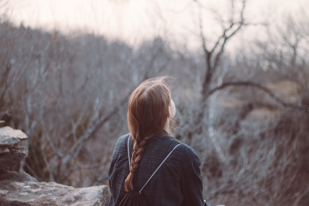 woman in black jacket sitting on rock during daytime