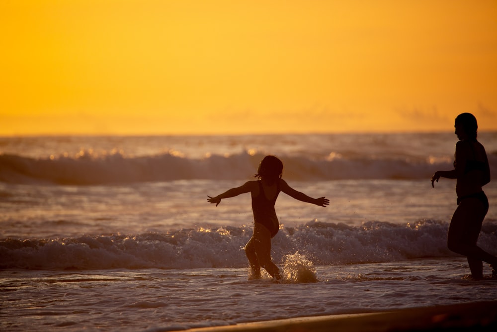 girl in black shirt and shorts running on beach during sunset