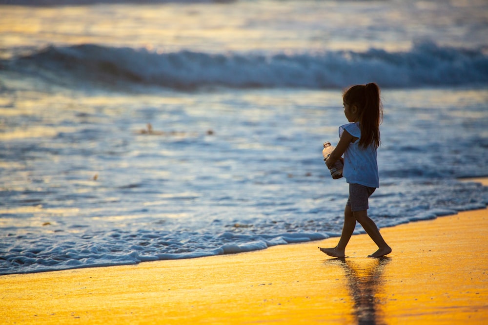 girl in white dress walking on beach during daytime