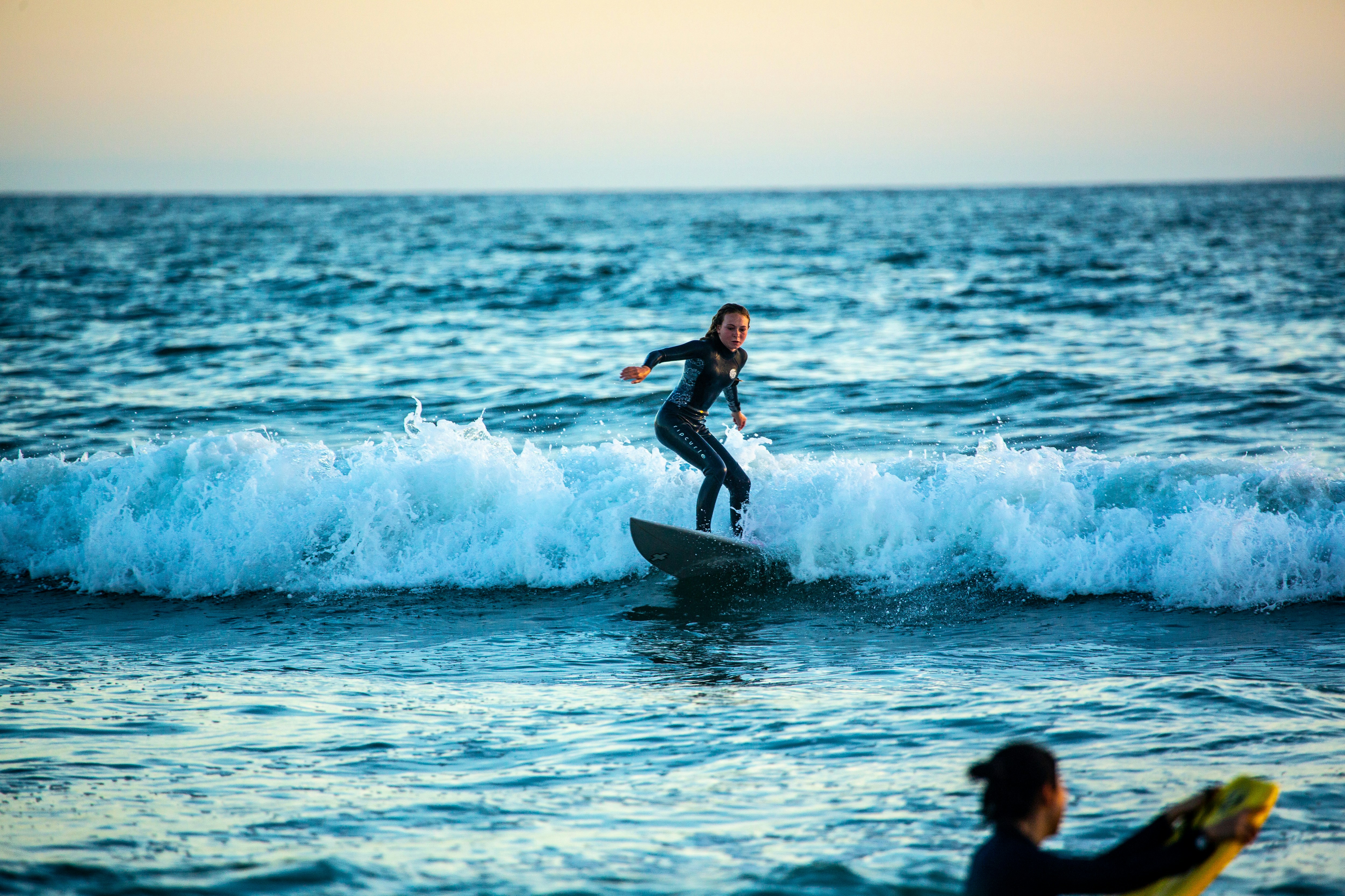Woman in black wetsuit surfing on sea waves during daytime photo Free