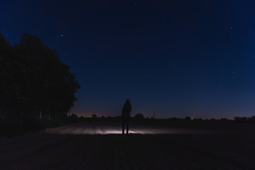 silhouette of person walking on sand during night time