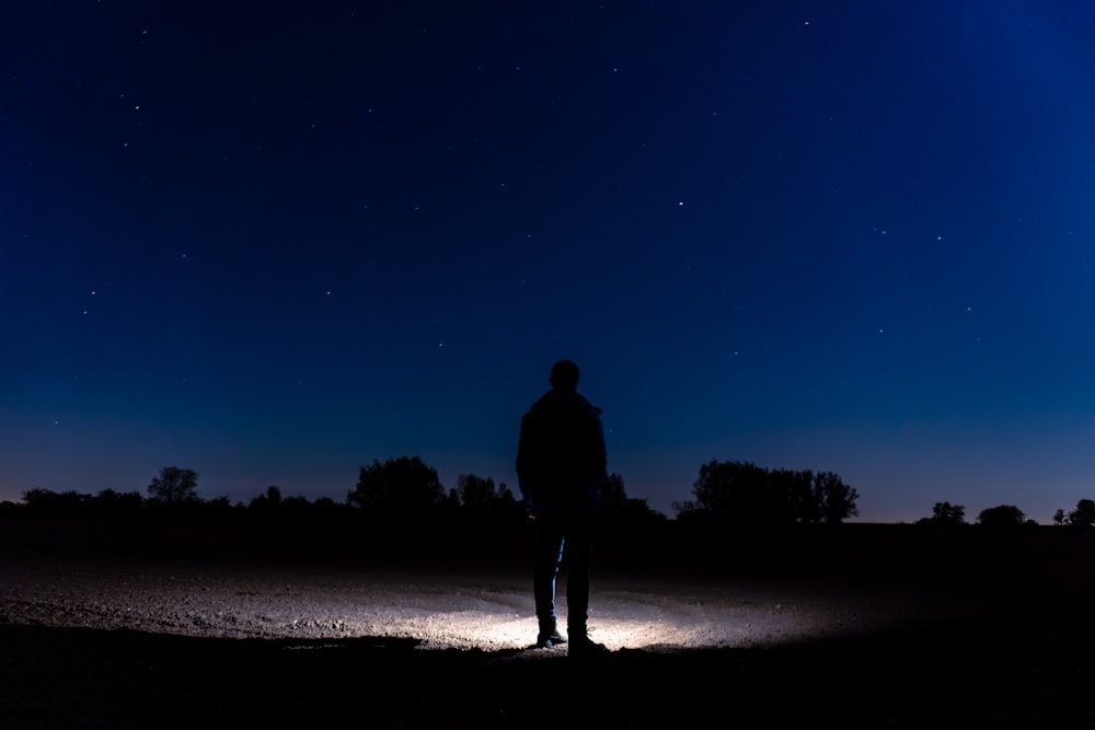 silhouette of man standing on beach during night time