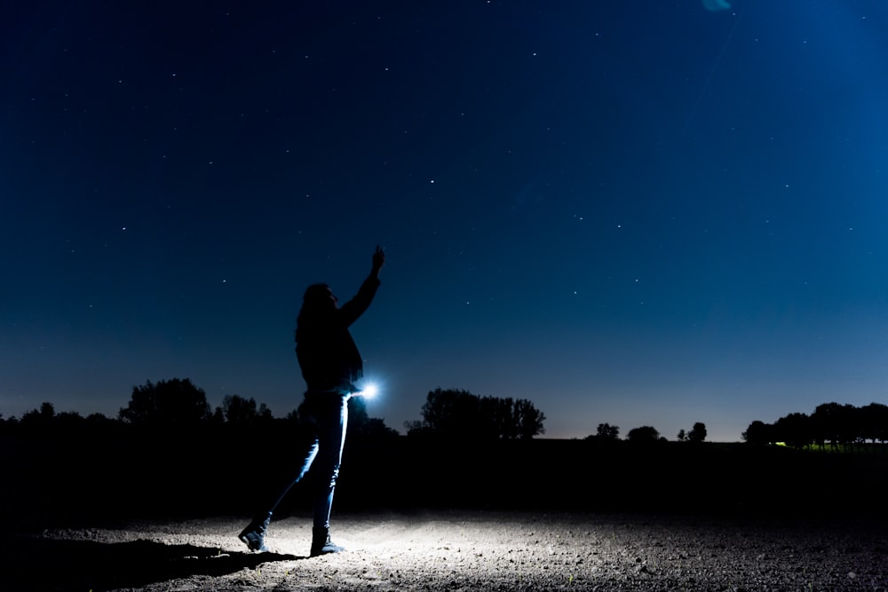 silhouette of person standing on sand during night time