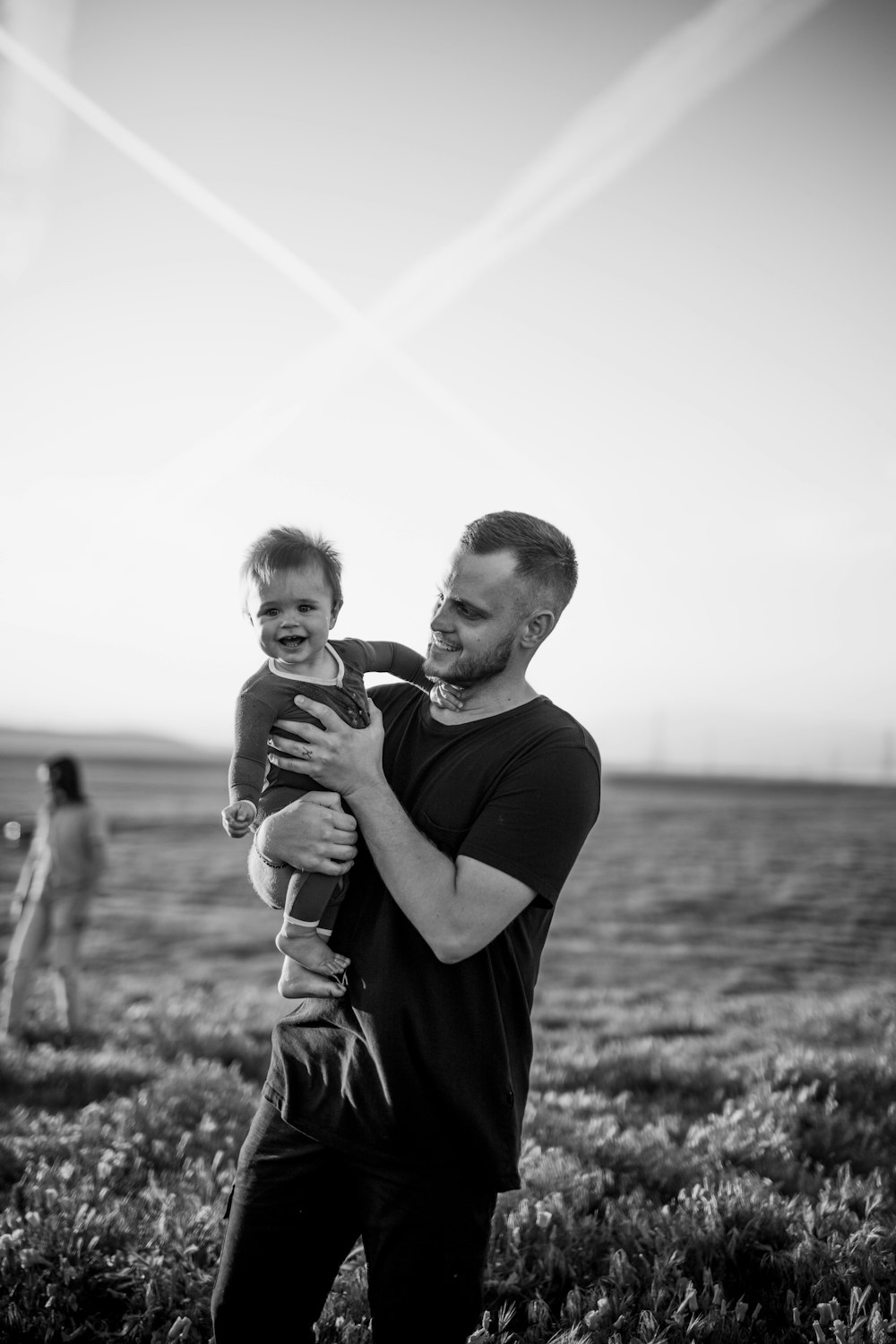 grayscale photo of man and boy standing on grass field