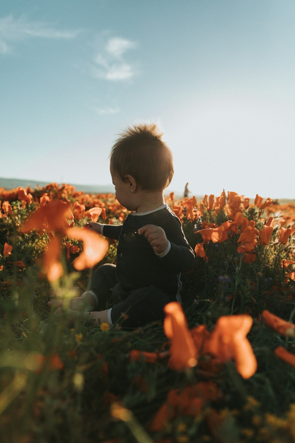 boy in black long sleeve shirt sitting on green grass field during daytime