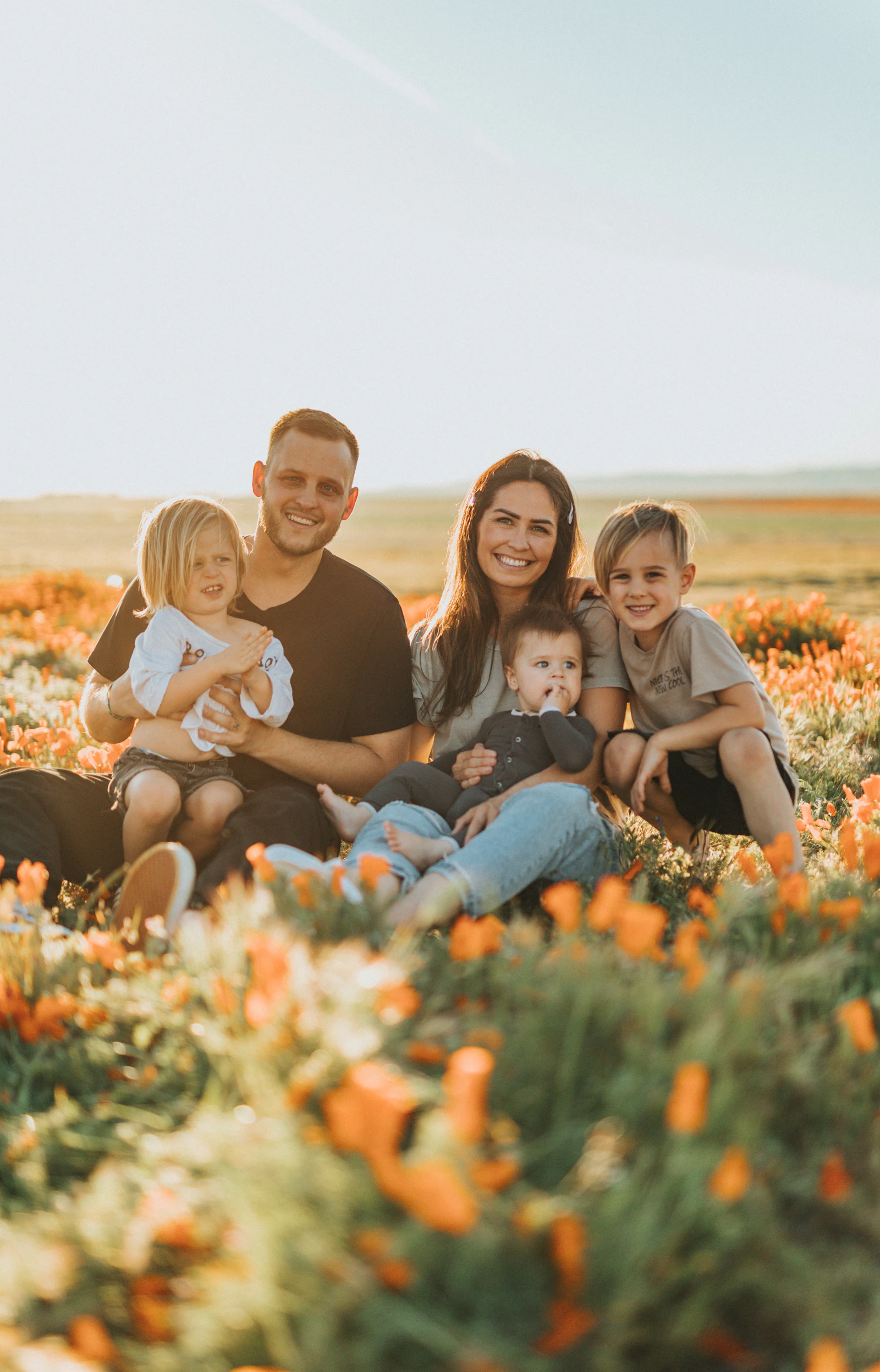 Family of five walking together through a golden wildflower field