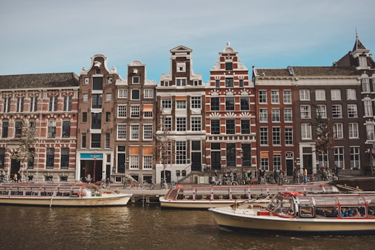 white and brown boat on body of water near brown concrete building during daytime in Westerkerk Netherlands