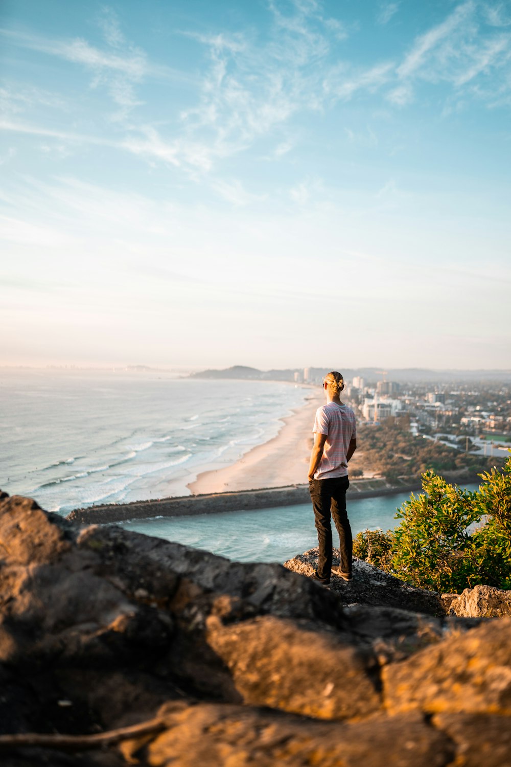 man in gray long sleeve shirt standing on rock near body of water during daytime