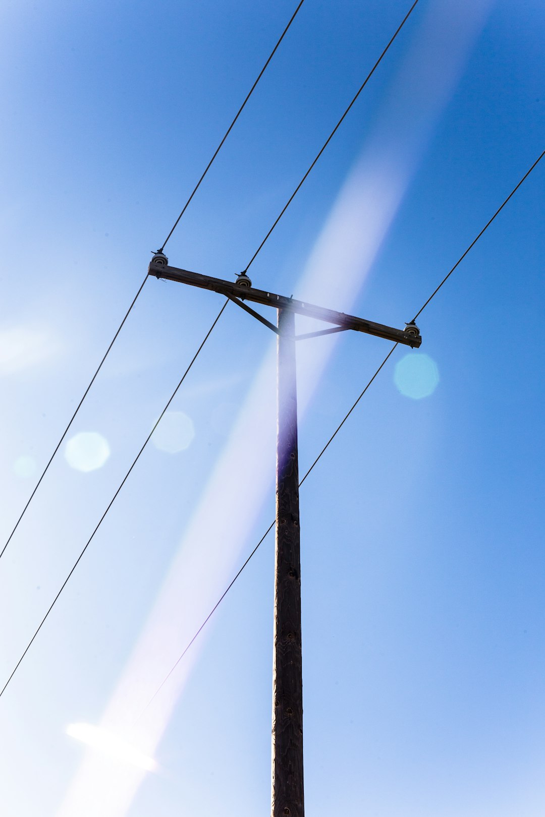 brown wooden electric post under blue sky during daytime