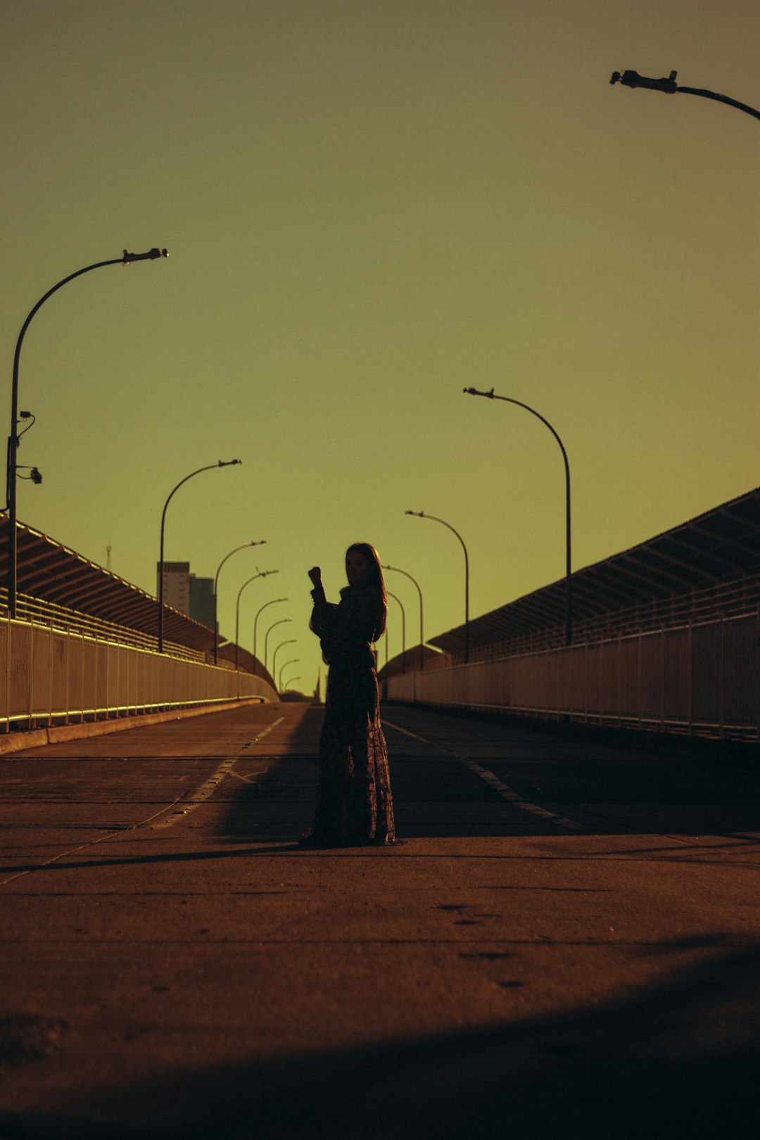 silhouette of woman standing on road during sunset
