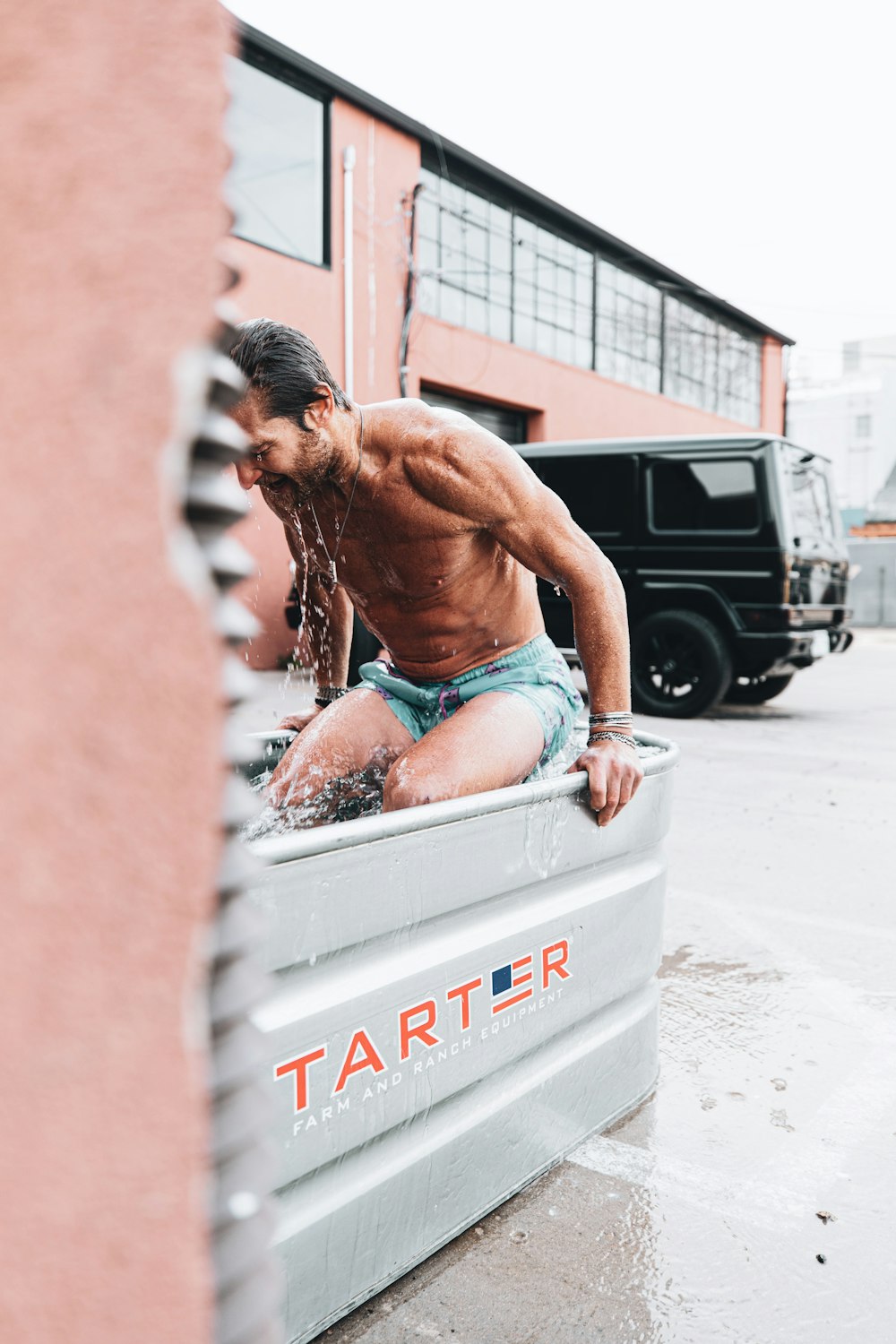 topless man in blue denim shorts sitting on white plastic crate