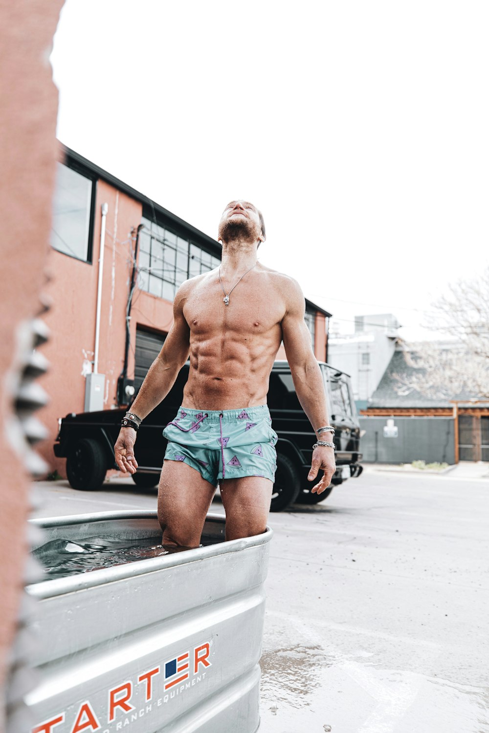 topless man in blue and white shorts standing on sidewalk during daytime