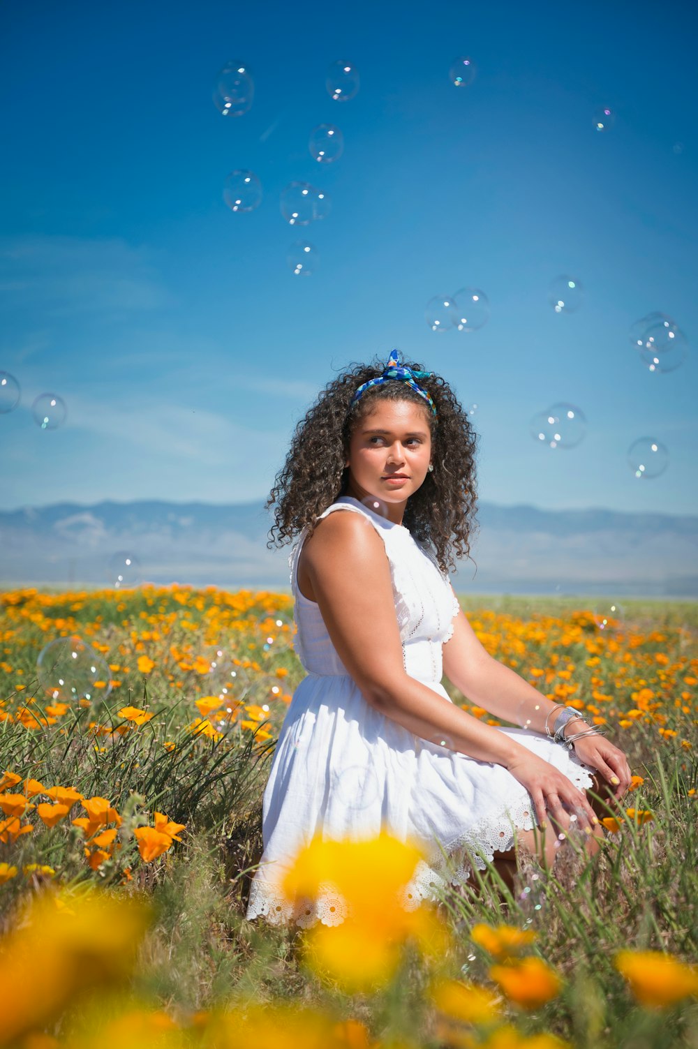 girl in white sleeveless dress standing on yellow flower field during daytime