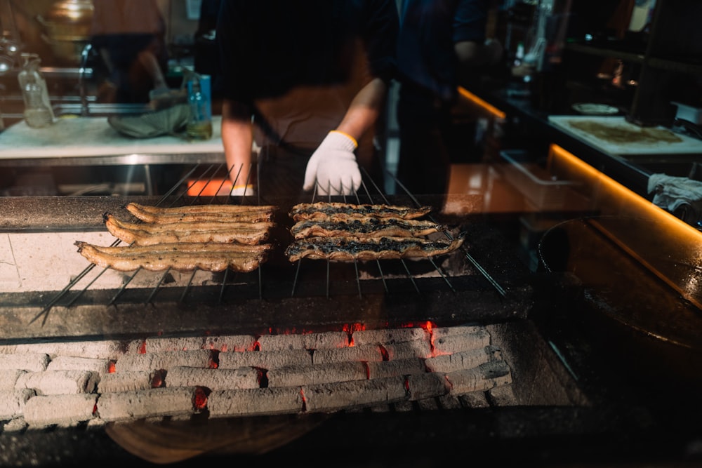 person in black shirt and white pants standing in front of grill