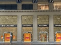 A luxury storefront with a lavish gold-accented facade, featuring prominent branding of the name 'BVLGARI'. The store displays have illuminated windows showcasing products, with elegant design and decor elements. The overall aesthetic conveys sophistication and opulence.
