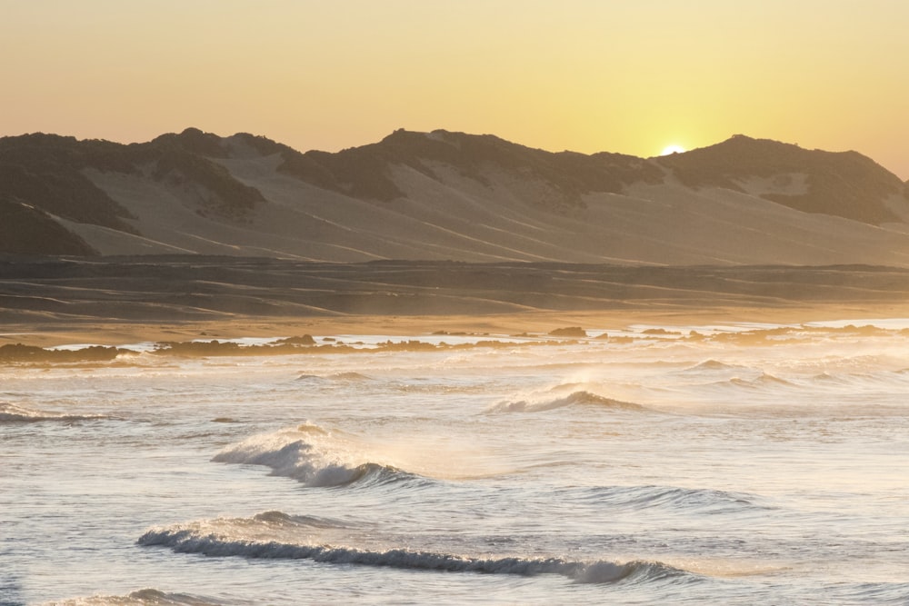 sea waves crashing on shore during sunset