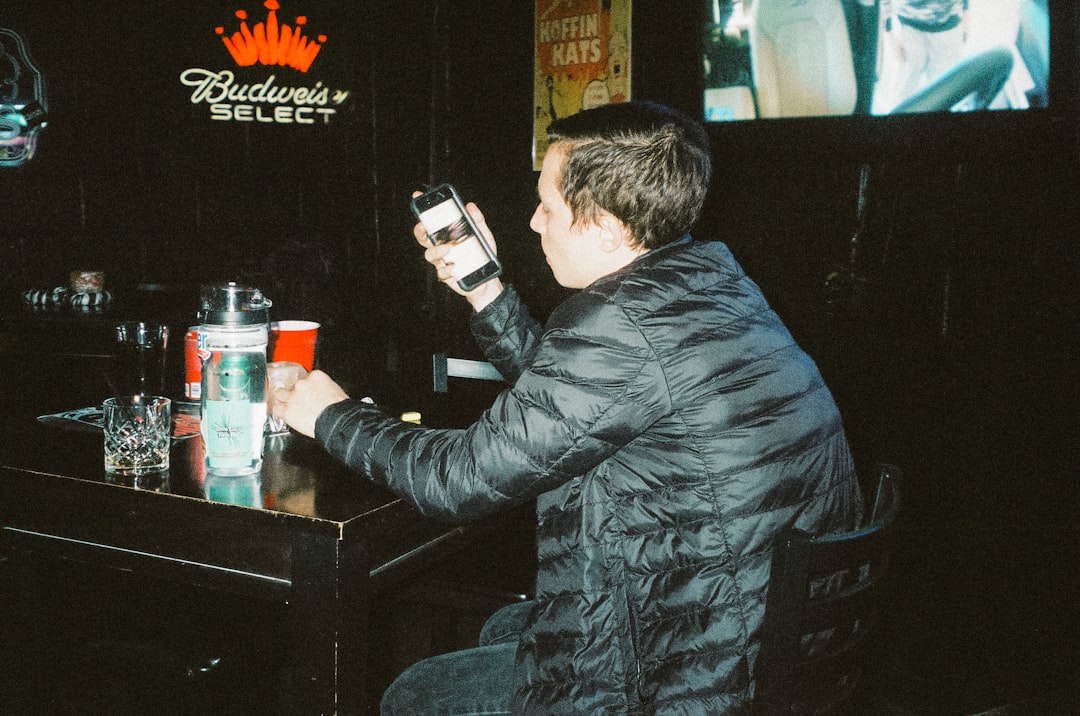 man in black leather jacket holding black smartphone