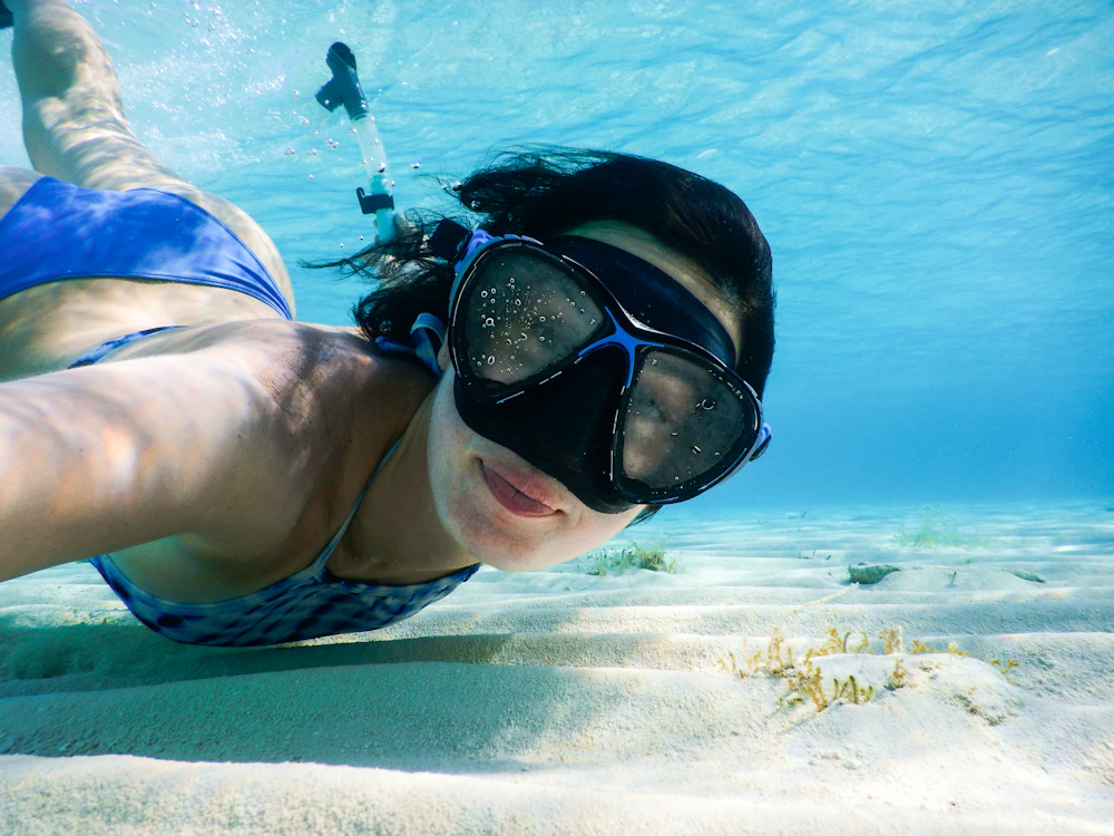 A swimmer in goggles underwater in the lagoon