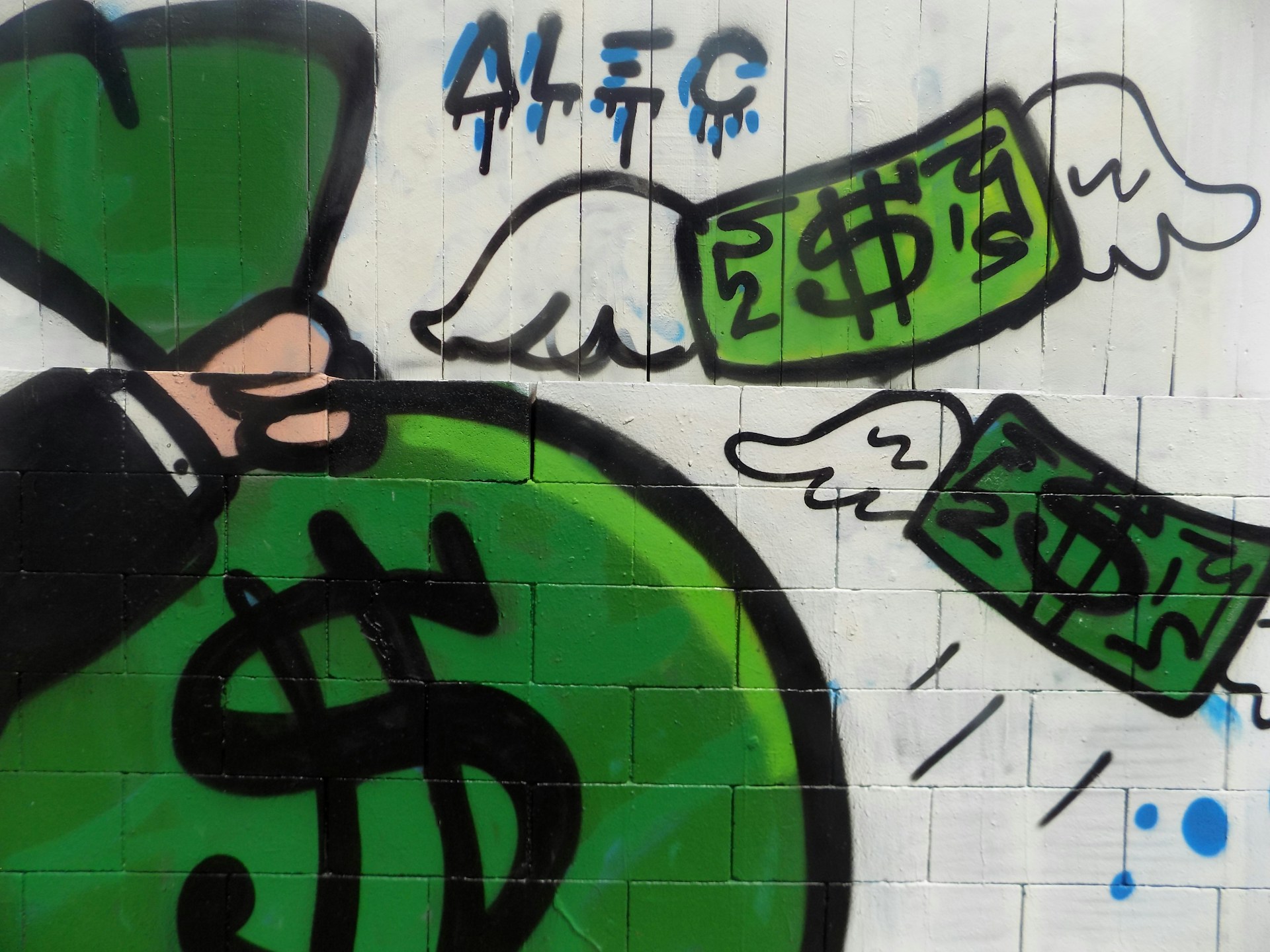woman in black tank top and black sunglasses standing beside white wall with green graffiti
