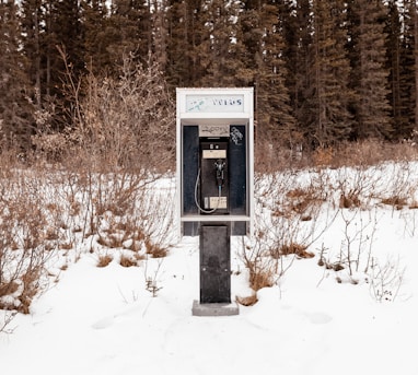 black and gray telephone booth on snow covered ground