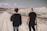 man in black shirt and blue denim jeans walking on beach during daytime
