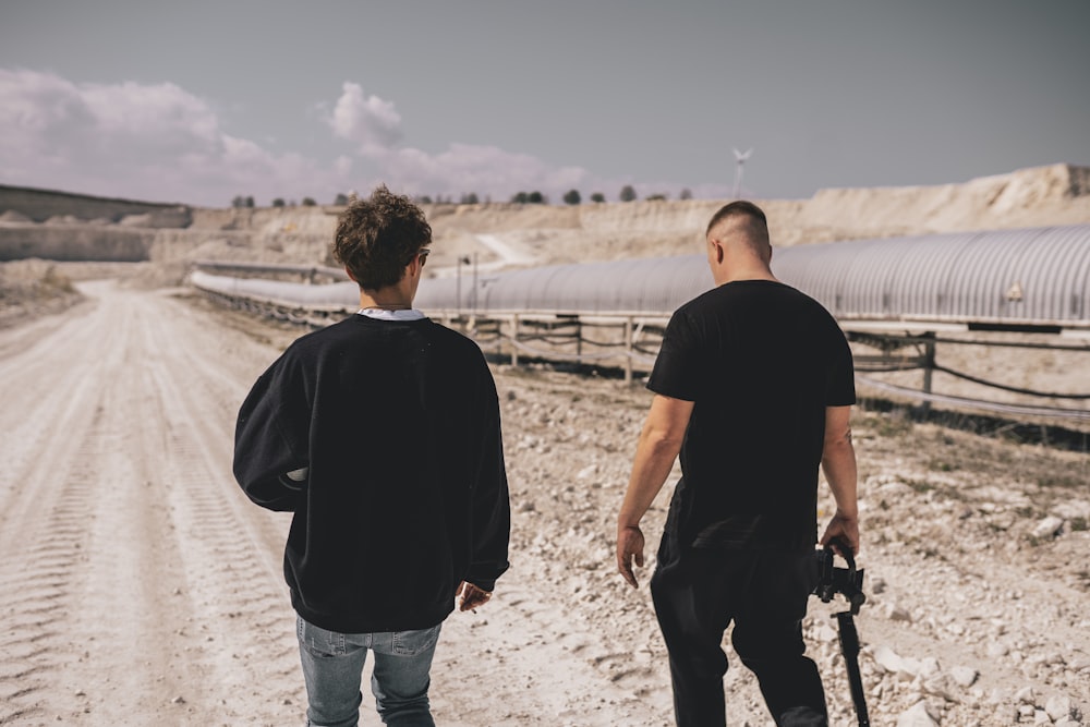 man in black shirt and blue denim jeans walking on beach during daytime