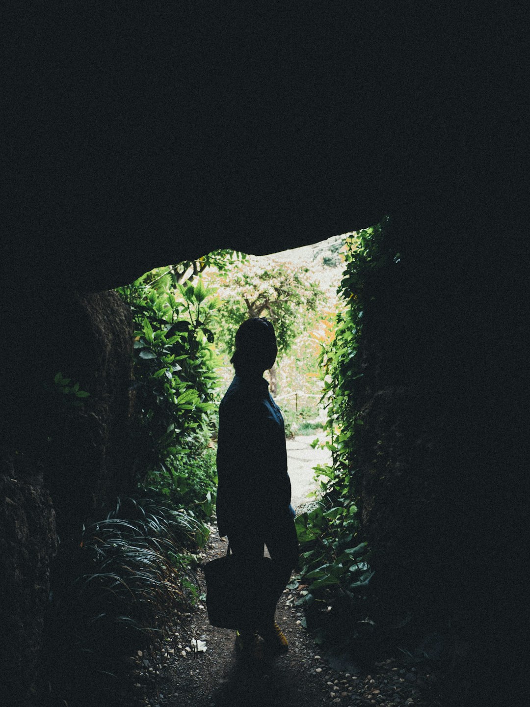 silhouette of person standing in cave during daytime