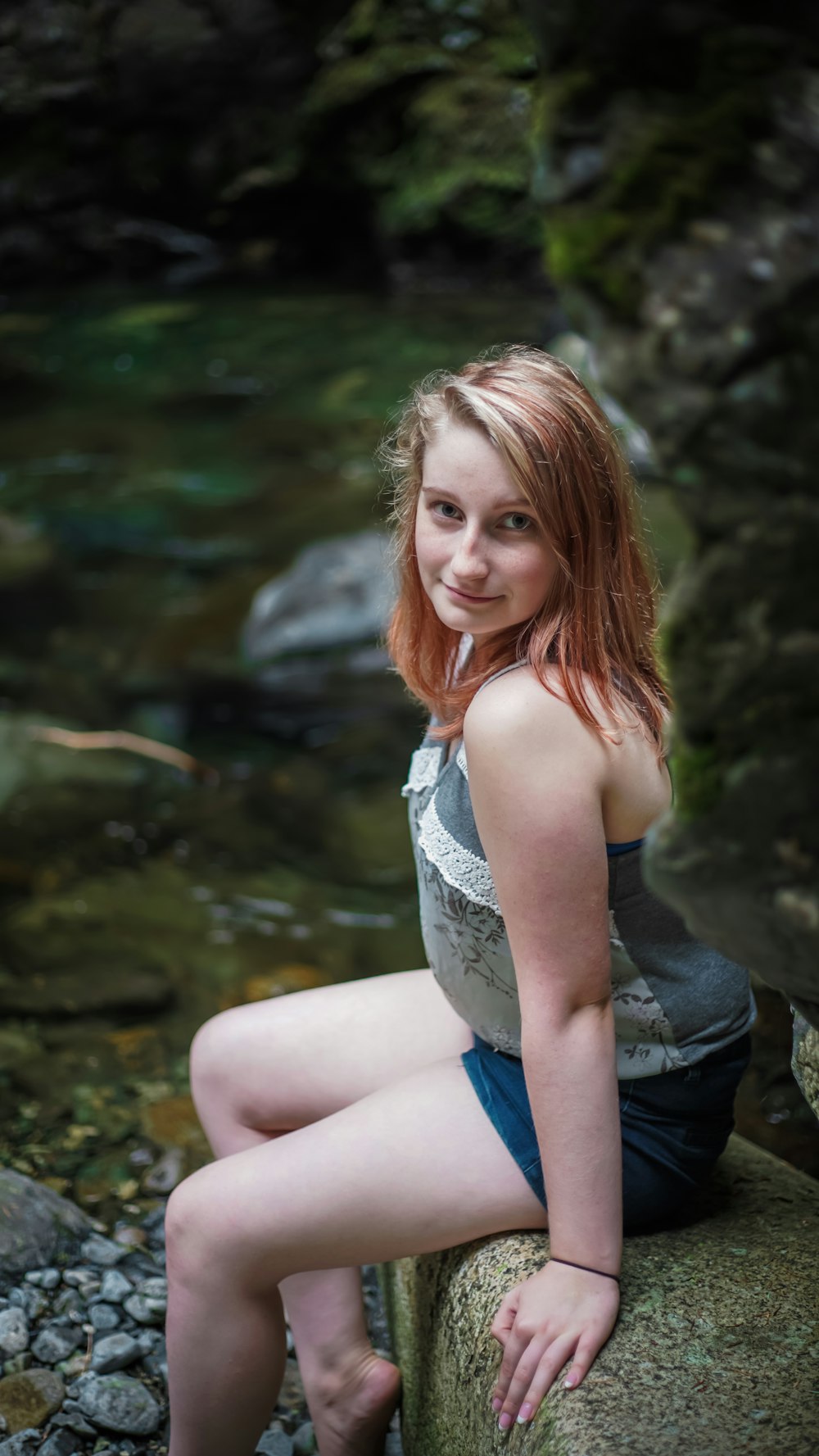 woman in gray tank top and blue denim shorts sitting on rock