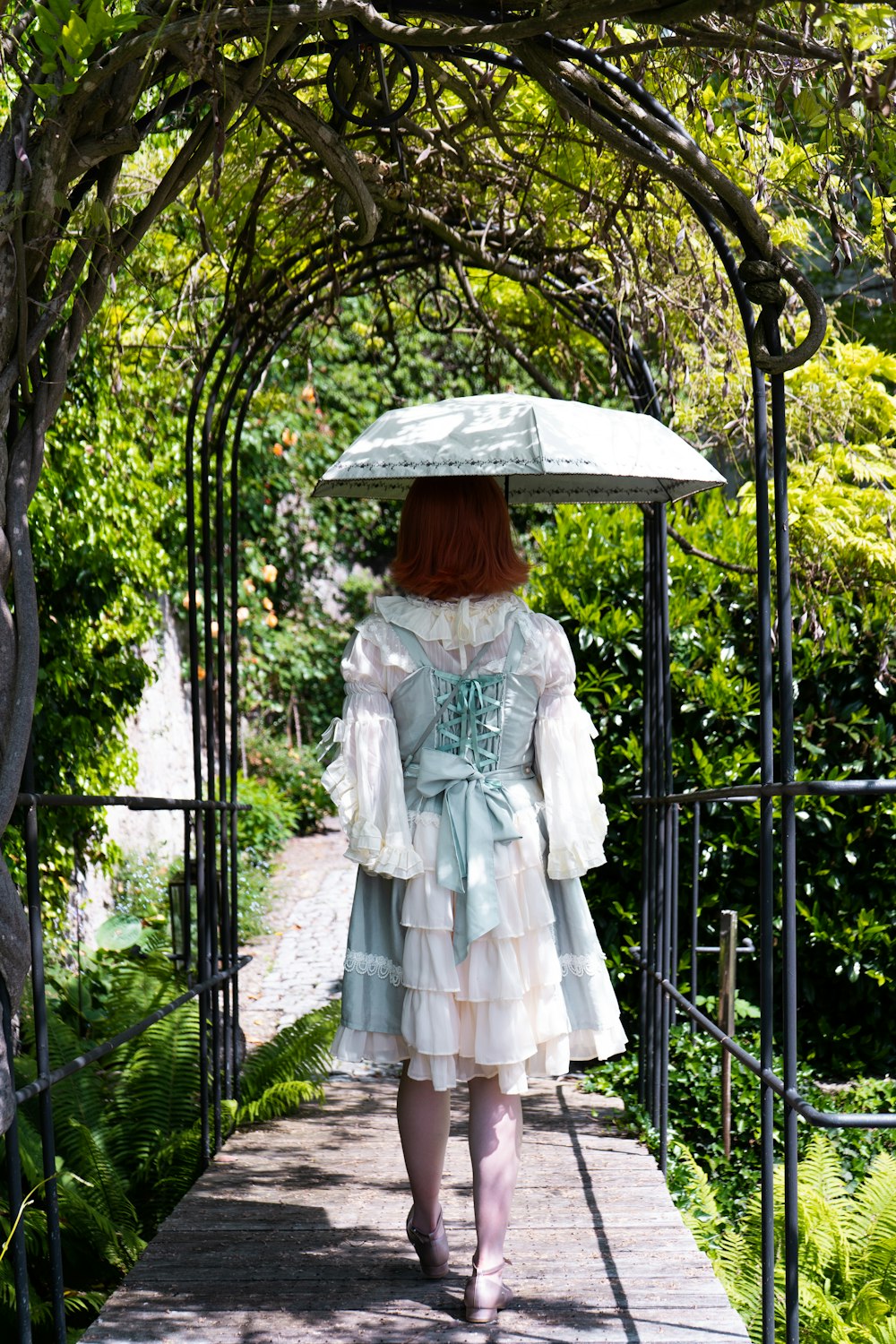 woman in white dress standing on black metal fence