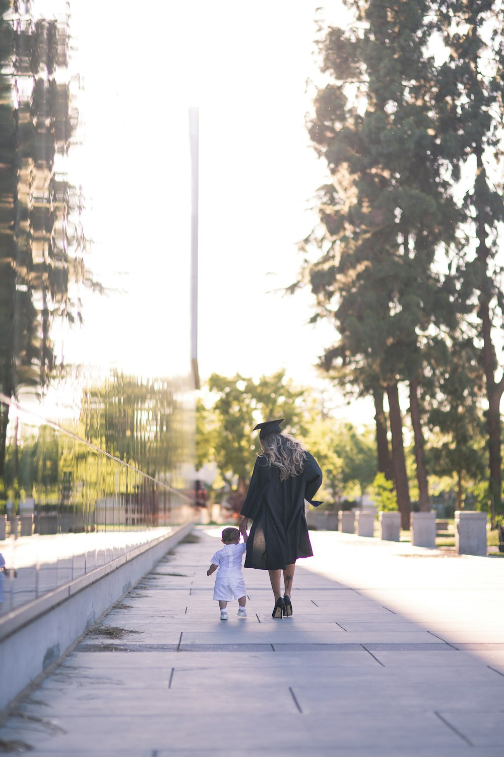 Persona in felpa con cappuccio nera che cammina sul marciapiede durante il giorno