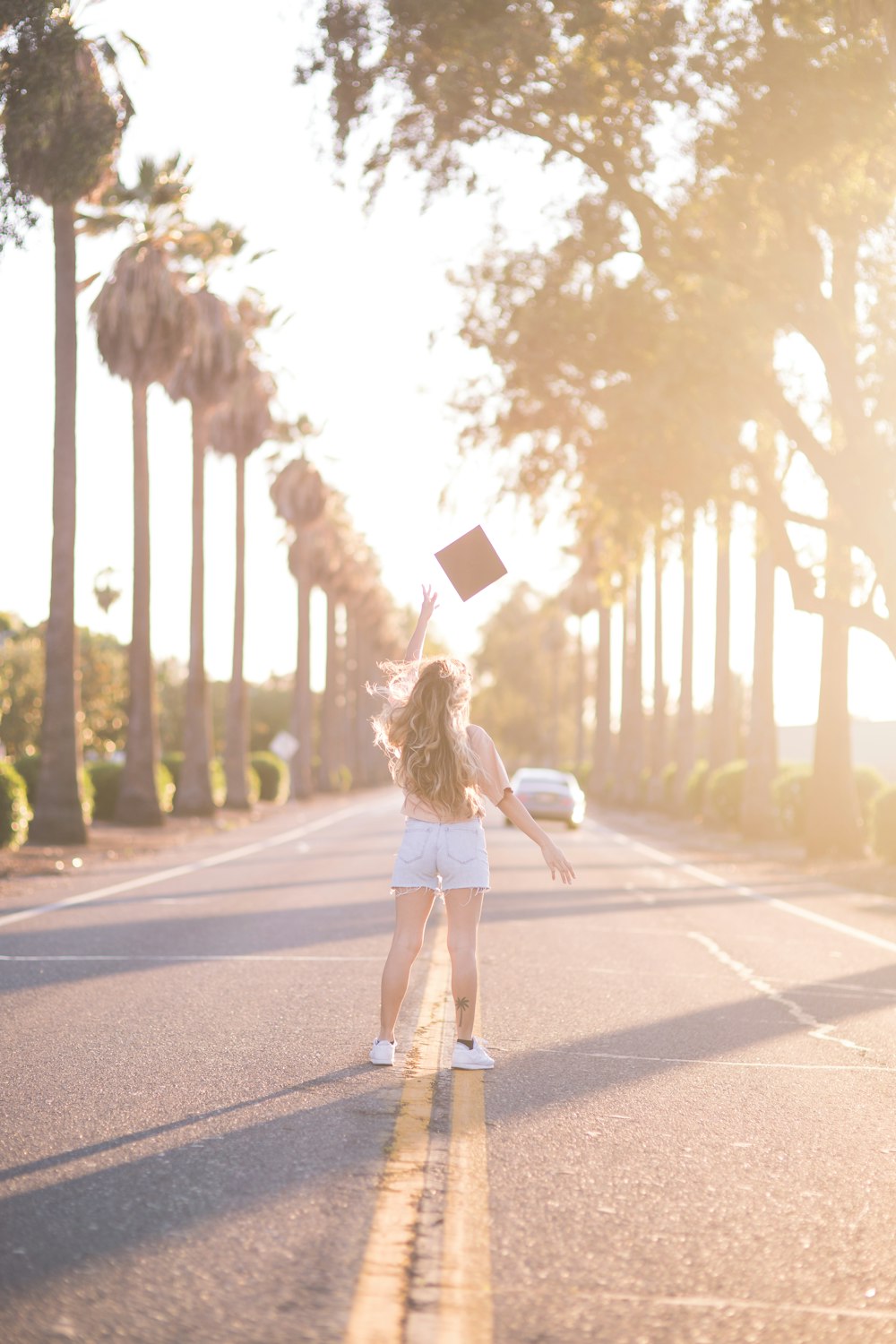 Femme en mini-robe blanche tenant un sac en papier brun debout sur la route pendant la journée