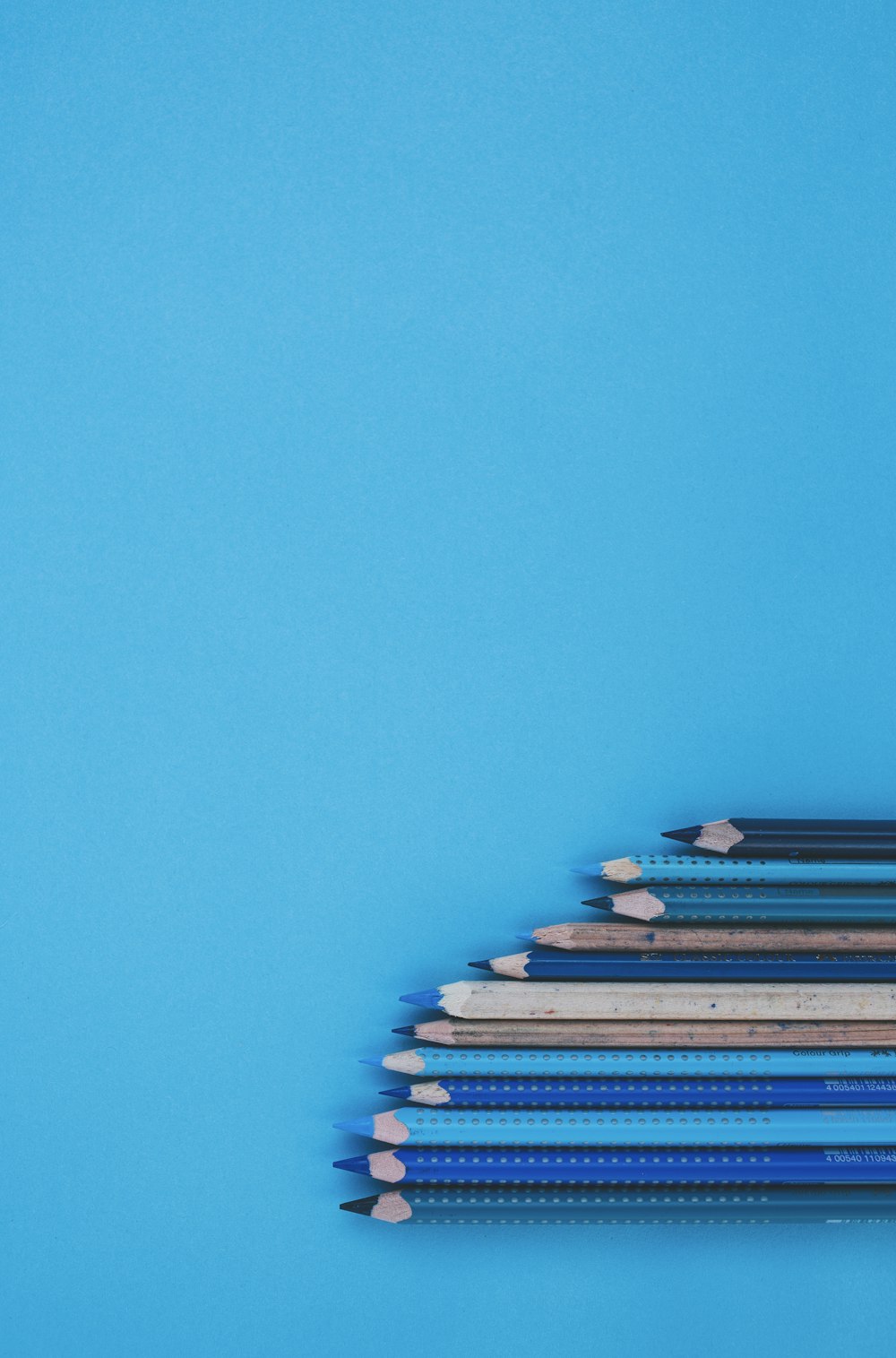 blue and white pencils on teal surface