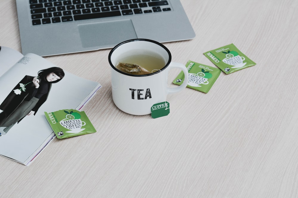 white ceramic mug beside green and white box