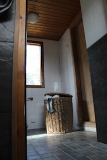 A bamboo laundry basket placed in a modern bathroom.