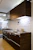 A modern modular kitchen setup blending sleek wood and metal finishes, fitting perfectly in a 3 BHK apartment.